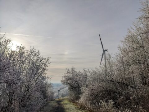 Windkraftanlage in einer mit Puderschnee bedeckten Winterlandschaft